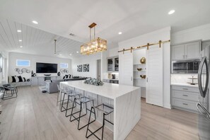 A modern kitchen with a large island, bar stools, and a built-in oven. - Beachfront • Outdoor Lounge + Parking (Bolivar Peninsula)
