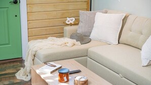 Ein gemütliches Wohnzimmer mit einem Ecksofa, einem Holztisch und einer grünen Tür.