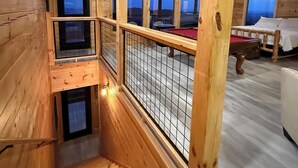 Eine Holzhütte mit Balkon, Billardtisch und Treppe.
