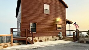Ein Holzhaus mit Veranda, Treppen und einer amerikanischen Flagge.