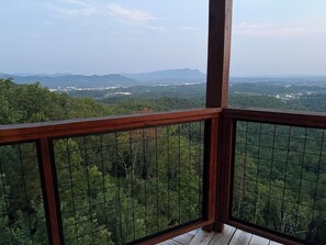 A balcony with a view of a forested landscape and distant mountains. - Savannah Smiles (Sevierville)