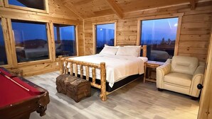Ein Schlafzimmer in einer Holzhütte mit einem Bett, einem Sessel und einem Billardtisch.