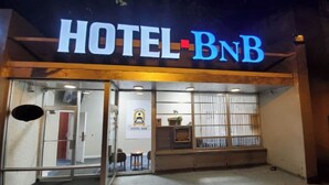 Exterior del Hotel BNB, con entrada de vidrio, un mostrador de recepción y un cartel.