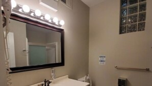 Un baño con tocador, lavamanos, espejo y retrete.