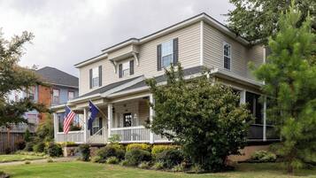 A two-story house with a front porch, a flag, and a well-maintained lawn.