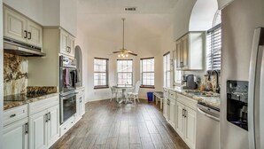 Une cuisine spacieuse avec des meubles blancs, un îlot central et un ventilateur de plafond.