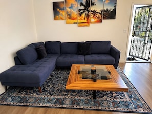 A modern living room with a sectional sofa, a glass coffee table, and a patterned rug. - Stylish 2BR Patio, BBQ and Parking (Los Angeles)