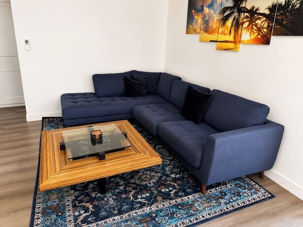 A modern living room with a sectional sofa, a glass coffee table, and a patterned rug. - Stylish 2BR Patio, BBQ and Parking (Los Angeles)