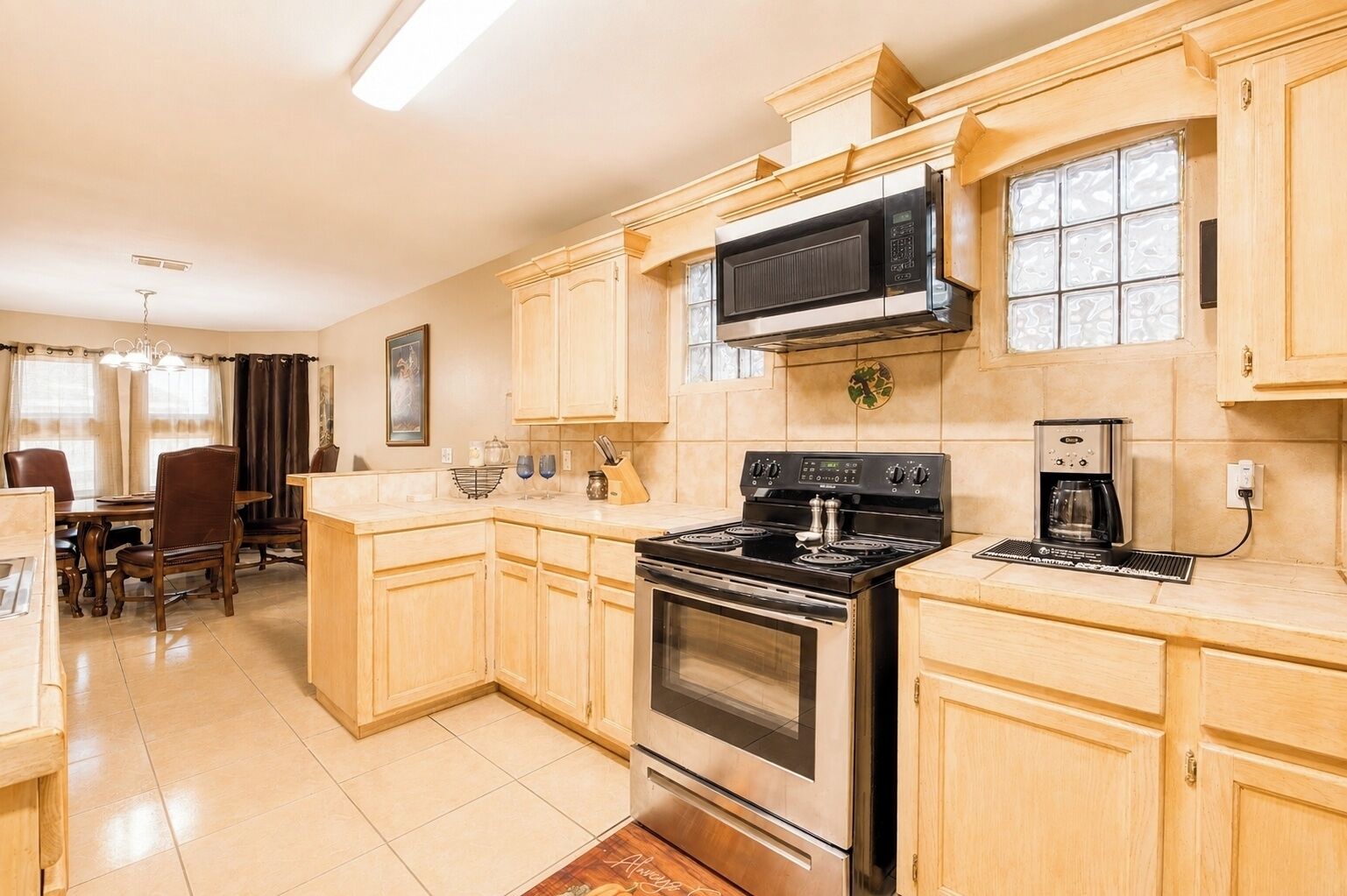 A kitchen with wooden cabinets, a stainless steel stove, a microwave, and a coffee maker.