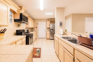 A kitchen with wooden cabinets, a microwave, stove, refrigerator, and a sink. - Covered Patio • Grill • Fenced Yard • Near LaPlaza (Pharr)