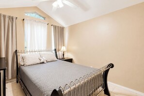 Une chambre à coucher avec un lit, des tables de chevet, une lampe et une fenêtre avec des rideaux.