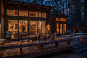 Eine moderne Holzhütte mit Terrasse, Sitzgelegenheit im Freien und großen Fenstern.