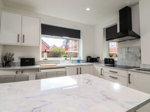 A modern kitchen with white cabinets, a marble countertop, and a black range hood.