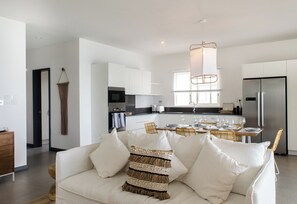 A modern kitchen with white cabinets, a stainless steel refrigerator, and a dining area with a table set for four. - O'biches by Horizon Holidays (Trou aux Biches)