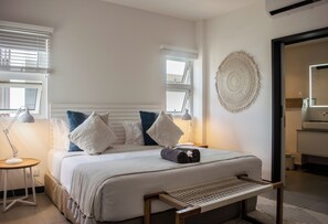 A neatly made bed with pillows, a bedside lamp, and a wall-mounted decorative item. - O'biches by Horizon Holidays (Trou aux Biches)
