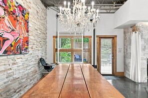 Une pièce spacieuse avec une table en bois, un lustre et un grand tableau abstrait accroché au mur.