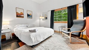 Habitación de hotel con cama, una silla, un escritorio y una ventana con cortinas.