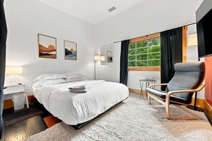 Een hotelkamer met een bed, een stoel, een bureau en een raam met gordijnen.
