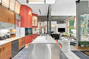 Una cocina moderna con una isla central, armarios de madera y una pared de acento roja.