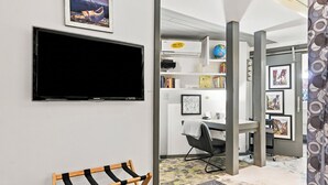 A modern room with a flat-screen TV mounted on the wall, a wooden chair, and a small table with a globe and books.