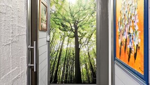 A hallway with a door leading to a forest view.