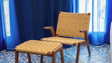 Una silla con respaldo y asiento tejido, patas de madera y un otoman a juego.