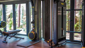 Un gimnasio con equipo de ejercicio, ventanas amplias y suelo de madera.