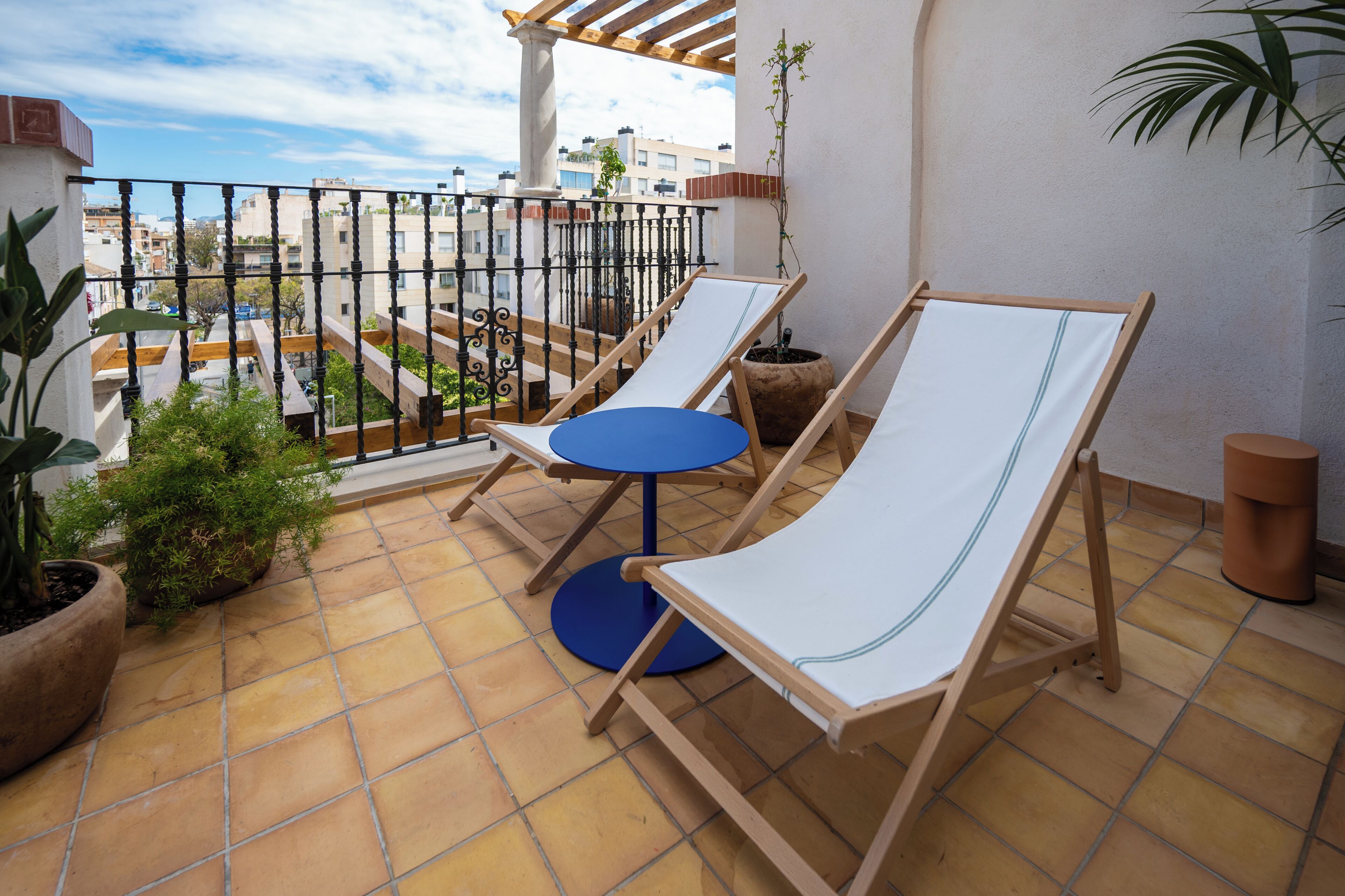 A balcony with two lounge chairs, a small round table, and potted plants.