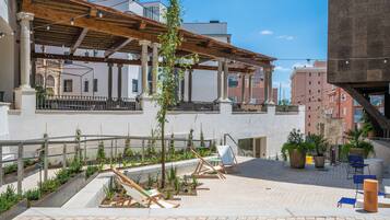An outdoor patio with seating, plants, and a pergola structure.