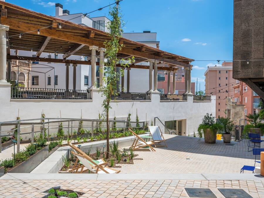 An outdoor patio with seating, plants, and a pergola structure.