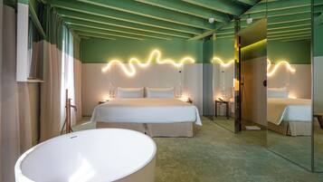 A hotel room with a large bed, a bathtub, and a mirror reflecting the room.