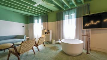 Una habitación con una bañera, un sofá y dos sillas.