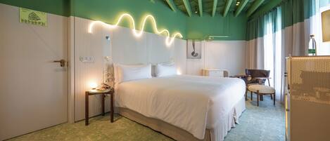 A hotel room with a large bed, a desk, a chair, and a wardrobe.