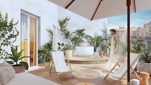 Un área de estar moderna al aire libre con sillones, una mesa redonda y plantas en macetas.