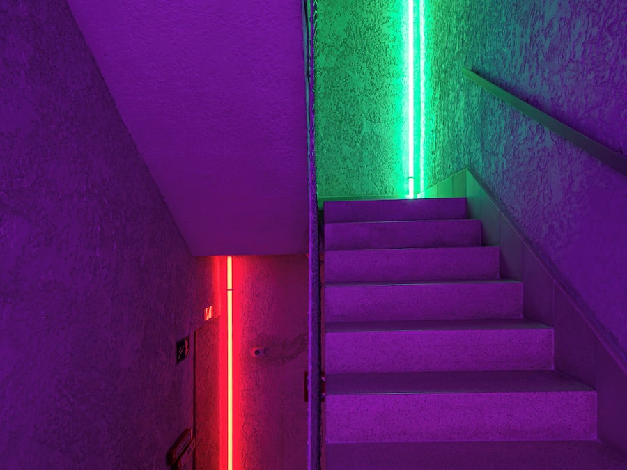 A staircase with a textured wall and a neon light.