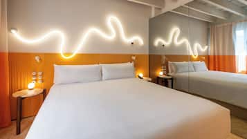 Habitación de hotel con dos camas, un espejo, una mesita de noche con lámpara y un aplique de pared.