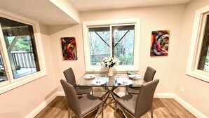 Un coin repas avec une table en verre, quatre chaises et deux fenêtres.