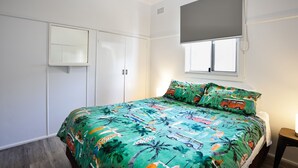 Ein Schlafzimmer mit Bett, Kleiderschrank, Fenster und Nachttisch.