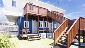 Une maison à deux étages avec une terrasse en bois et un escalier menant à un balcon.