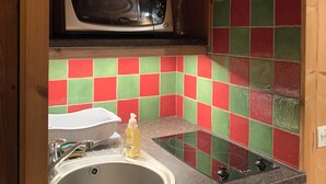 Une cuisine compacte équipée d’un four à micro-ondes, d’un évier et d’un plan de travail coloré recouvert de carreaux.