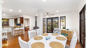 Uma cozinha espaçosa com armários brancos, uma ilha central e uma área de jantar com mesa e cadeiras redondas.