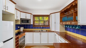 Uma cozinha compacta com armários brancos, micro-ondas, fogão e pia.