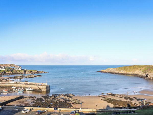 A coastal town with a harbor, boats, and a sandy beach. - 2 Harbour Lights (Cemaes Bay)