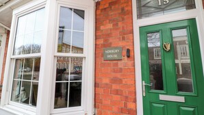 Una casa tradicional con una puerta verde, una ventana con marco blanco y un letrero que dice "NORBURY HOUSE".