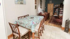Un área de comedor con una mesa y sillas, un sofá, una estantería y un cuadro en la pared.