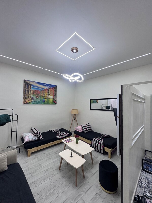 A modern room with a bed, a small table, and a painting on the wall.