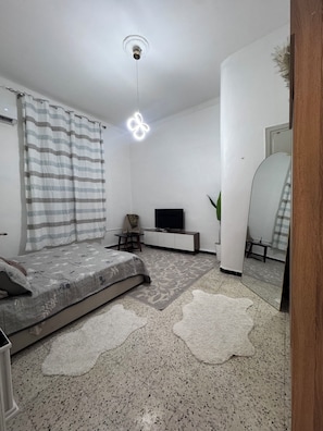 A modern living room with a sofa, TV, and a large mirror.