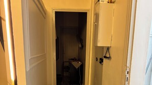 En hall med en mönstrad matta, en dörr som leder till ett annat rum och en väggmonterad elcentral.