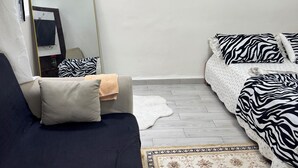 Ett sovrum med en säng, en soffa, en spegel och en målning som föreställer en kanalvy.