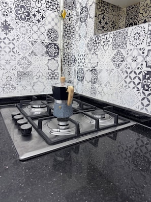 A kitchen with a gas stove, a coffee maker, and a patterned backsplash. - Cozy two-bedroom apartment in the heart of Algiers (Alger Centre)